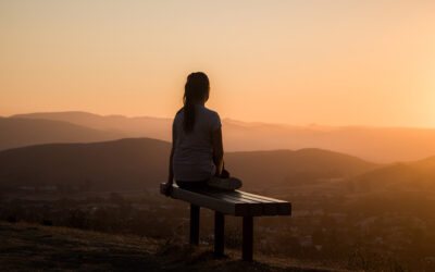 Een vrouw zit op een bankje en kijkt uit op het uitzicht op heuvels tijdens een zonsopgang