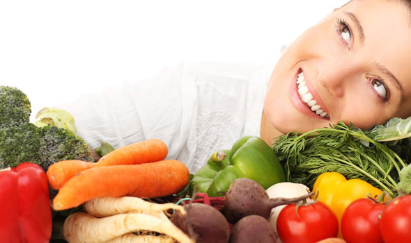 Een glimlachende vrouw met verschillende groenten